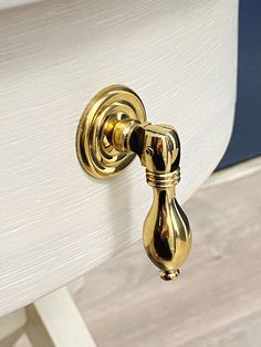 a close up of a gold door handle on a white chair