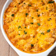 a casserole dish with meat and cheese in it sitting on a wooden table