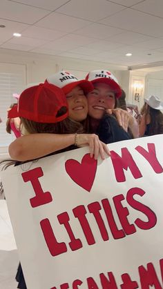 two women hugging each other while holding a sign that says i love my littles