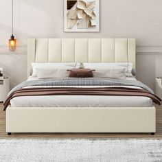 a white bed sitting on top of a wooden floor next to a wall mounted painting