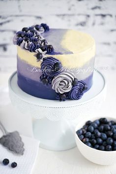 a blue and yellow cake sitting on top of a white plate next to some berries