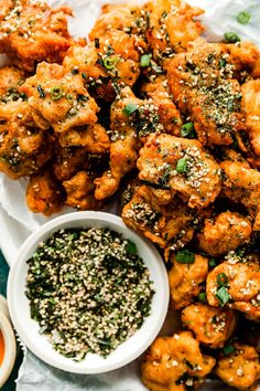 a white plate topped with chicken wings covered in sesame seeds and garnishes