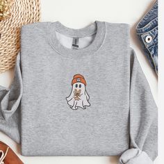 Get ready to embrace the cozy vibes of the fall season with our adorable "Cute Ghost with Dog" Crewneck Sweatshirt. Perfect for dog lovers and fans of cute, spooky designs, this sweatshirt is a must-have addition to your autumn wardrobe. Product Details: Material: Crafted from a comfortable and durable 50/50 cotton polyester blend, ensuring a soft feel and long-lasting wear. Sizes Available: S, M, L, XL, 2XL - fits true to size. Colors Available: Ash, Sport Grey, Dark Chocolate, Forest Green, Graphite Heather, Maroon, Military Green, Sand, Sport Grey, White. Design: Features a charming embroidered design of a cute ghost holding a dog, perfectly centered on the chest. This stylish design is ideal for the fall season, bringing a touch of whimsy and warmth to your outfit. Care Instructions: M Gray Embroidered Logo Sweatshirt For Fall, Casual Letter Embroidery Sweater For Fall, Fall Crew Neck Sweatshirt With Embroidered Logo, Cozy Fall Sweatshirt With Letter Embroidery, Cozy Sweatshirt With Letter Embroidery For Fall, Cozy Letter Embroidery Sweatshirt For Fall, Casual Embroidered Sweater For Fall, Fall Crew Neck Sweater With Letter Embroidery, Gray Letter Embroidery Sweatshirt For Fall