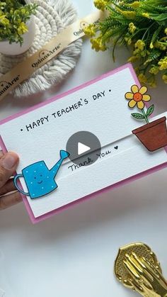 a person holding up a card that says happy teacher's day with a watering can