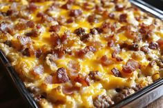 a casserole dish with cheese and bacon on it sitting on a wooden table