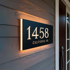 a house number sign mounted to the side of a building with lights on it's sides