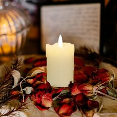 a lit candle sitting on top of a table surrounded by dried flowers and candlesticks