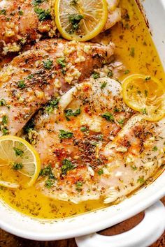 chicken with lemons and herbs in a white casserole