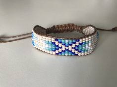 a blue and white beaded bracelet sitting on top of a table