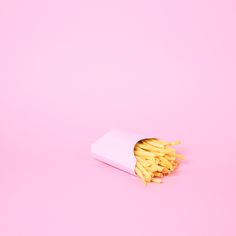 french fries in a paper bag on a pink background