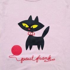 a black cat with yellow eyes is on a pink t - shirt that says paul frank