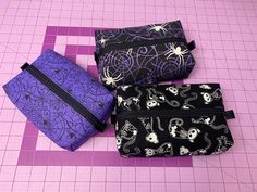 Dark and cute boxy zipper pouches that are perfect for holding all of your little things. Great size for pens, makeup, sewing notions, etc. Choose from 3 different outer fabrics. All three styles come with a deep purple lining, black zipper, and black ribbon tabs for an easy zipper close. Dimensions: 7 inches long, 5 inches wide, and 2 inches tall All Black Ankh Designs products are made in a smoke-free and cat-friendly home. Purple Pencil Case With Zipper Closure As Gift, Rectangular Zipper Pouch Cosmetic Bag For School, Rectangular Pencil Case With Zipper Closure As Gift, Rectangular Pencil Case With Zipper Pocket, Rectangular Purple Pencil Case, Purple Pencil Case With Zipper, Purple Rectangular Cosmetic Bag For School, Rectangular Zipper Pouch Craft Supplies, Purple Rectangular Pouch With Zipper Closure