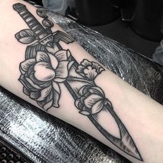 a black and white photo of a knife with flowers on the side of its arm