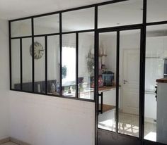 an empty room with black glass doors and tile flooring on one side, looking into the kitchen