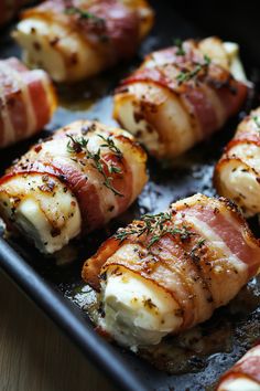 bacon wrapped chicken on a baking sheet with some seasoning sprinkled around it