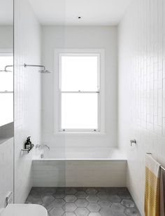 a bathroom with a tub, sink and window in it's center wall is shown