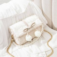 a white purse with pom - poms on it