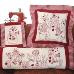 a red and white pillow with two snowmen on it next to a sewing machine