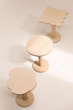 three wooden tables sitting side by side on top of a white surface with no one around them