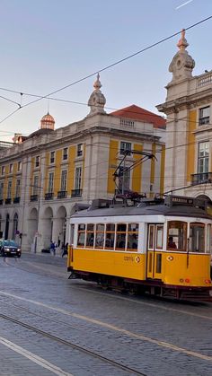 a yellow and white trolley car on street next to buildings