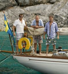 three men standing on the deck of a sailboat