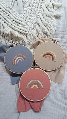 three different types of embroiderys on a bed with a tassell in the background