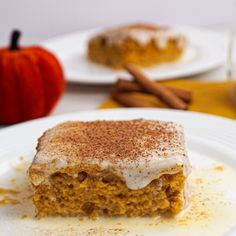 a piece of cake sitting on top of a white plate next to an orange pumpkin