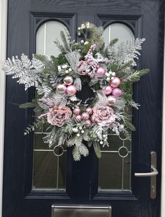 a wreath on the front door of a house decorated with pink and silver ornaments for christmas