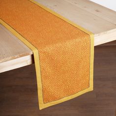 an orange and yellow table runner on top of a wooden bench with wood flooring