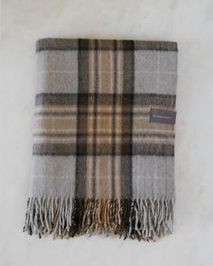 a tan and black plaid blanket laying on top of a white surface