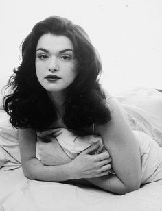 a black and white photo of a woman laying on a bed with her arms crossed