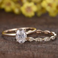 two gold wedding rings with an oval cut diamond