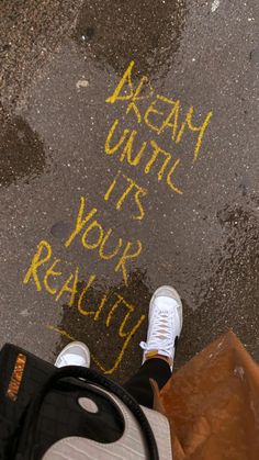 someone is standing on the sidewalk with their feet in the air and writing on the ground