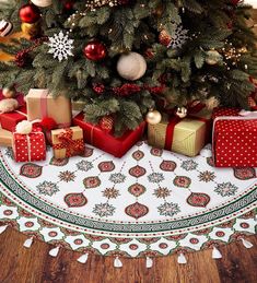 a christmas tree with presents under it in front of a white and red tablecloth