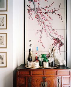 there are bottles and glasses on top of the dresser in this room with cherry blossoms