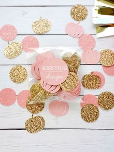 pink and gold pineapple confetti cutouts on a white table with feathers