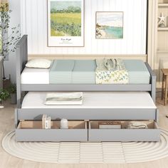 a day bed with drawers underneath it in a room that has white walls and wood floors