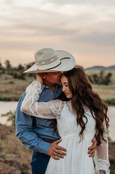 a man in a cowboy hat hugging a woman wearing a white dress and blue shirt