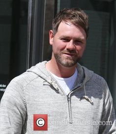 a man standing in front of a building with a red and white logo on it