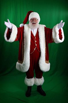 a man dressed as santa clause standing in front of a green background