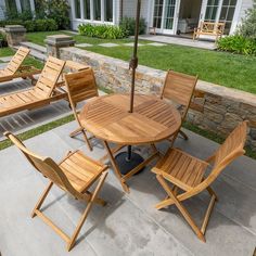 a patio with wooden chairs and an umbrella