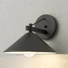 a wall light that is on the side of a white wall with a black shade