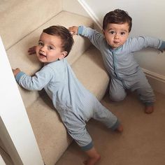 two young boys standing on the stairs in pajamas looking at the camera with their hands behind them