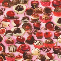 many different types of chocolates and cherries on a pink background