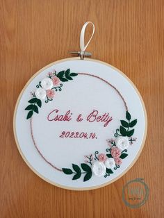 the embroidery is hanging on the wall with flowers and leaves around it that says caki & betty