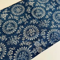 a blue table cloth with white flowers and leaves on it, sitting on top of a counter