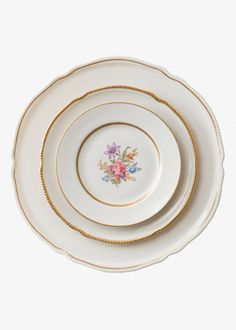 three plates stacked on top of each other with gold trimmings and floral designs