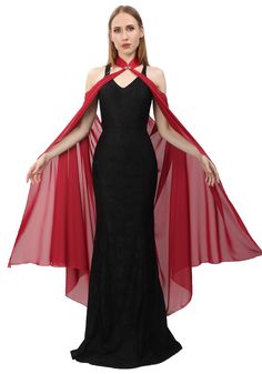 a woman in a black and red dress with cape on her head, wearing an evening gown