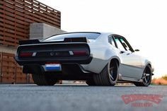 the rear end of a white car parked in front of a building