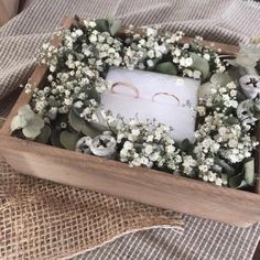 a wooden box filled with flowers and two wedding rings on top of the inside of it